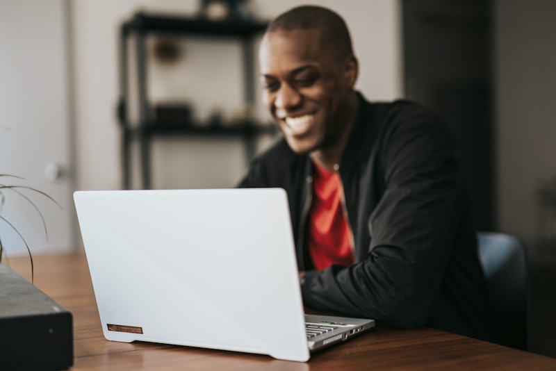 Man smiling while working on a laptop.