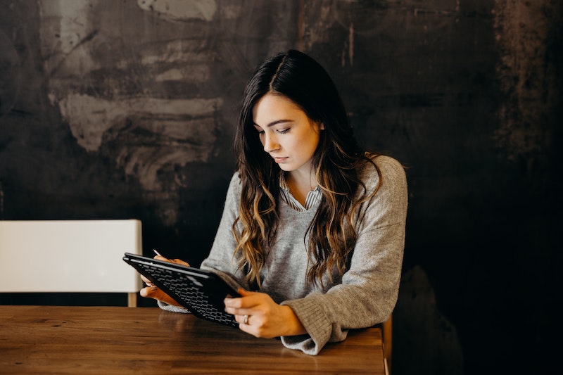 Woman on tablet at dining table.